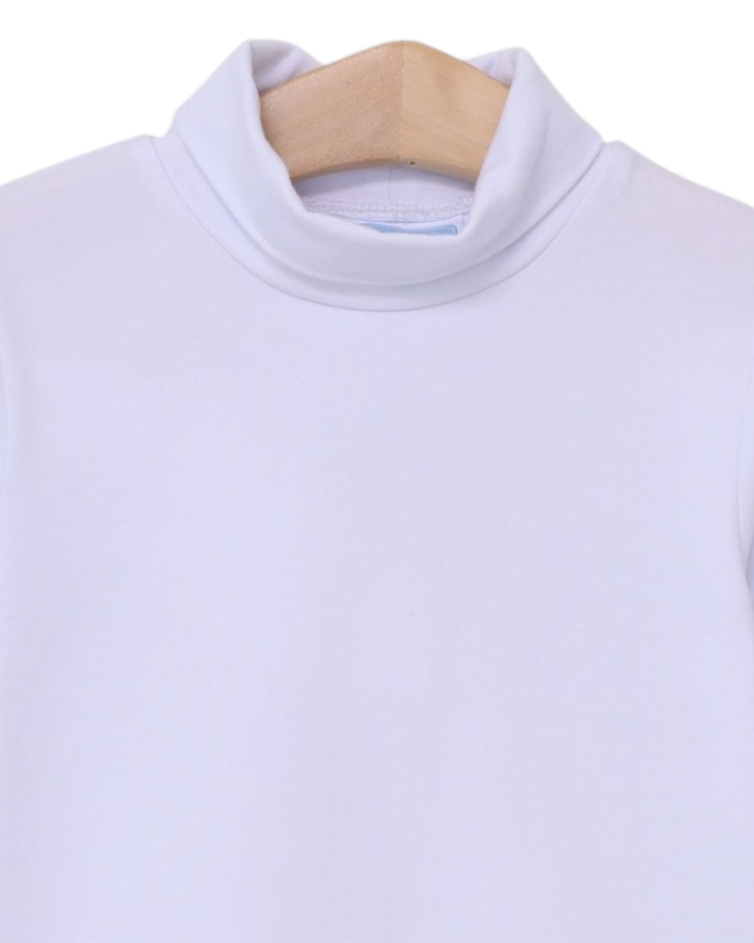 A close-up of a white mock neck turtleneck sweater hanging on a light wood hanger against a plain white background, that store