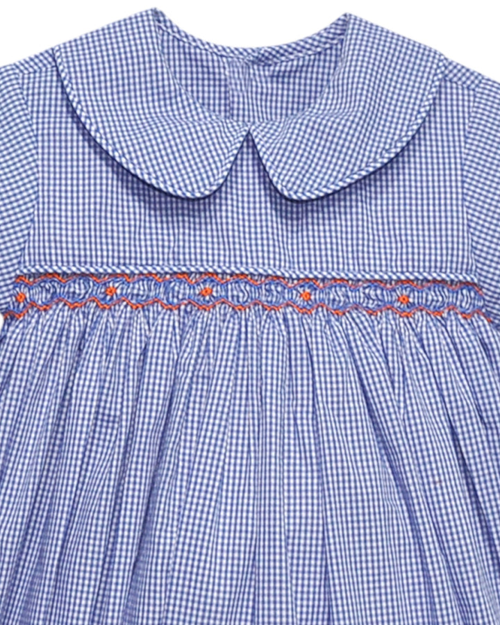 Close-up of a blue checkered dress with a smocked waistline and embroidered details.