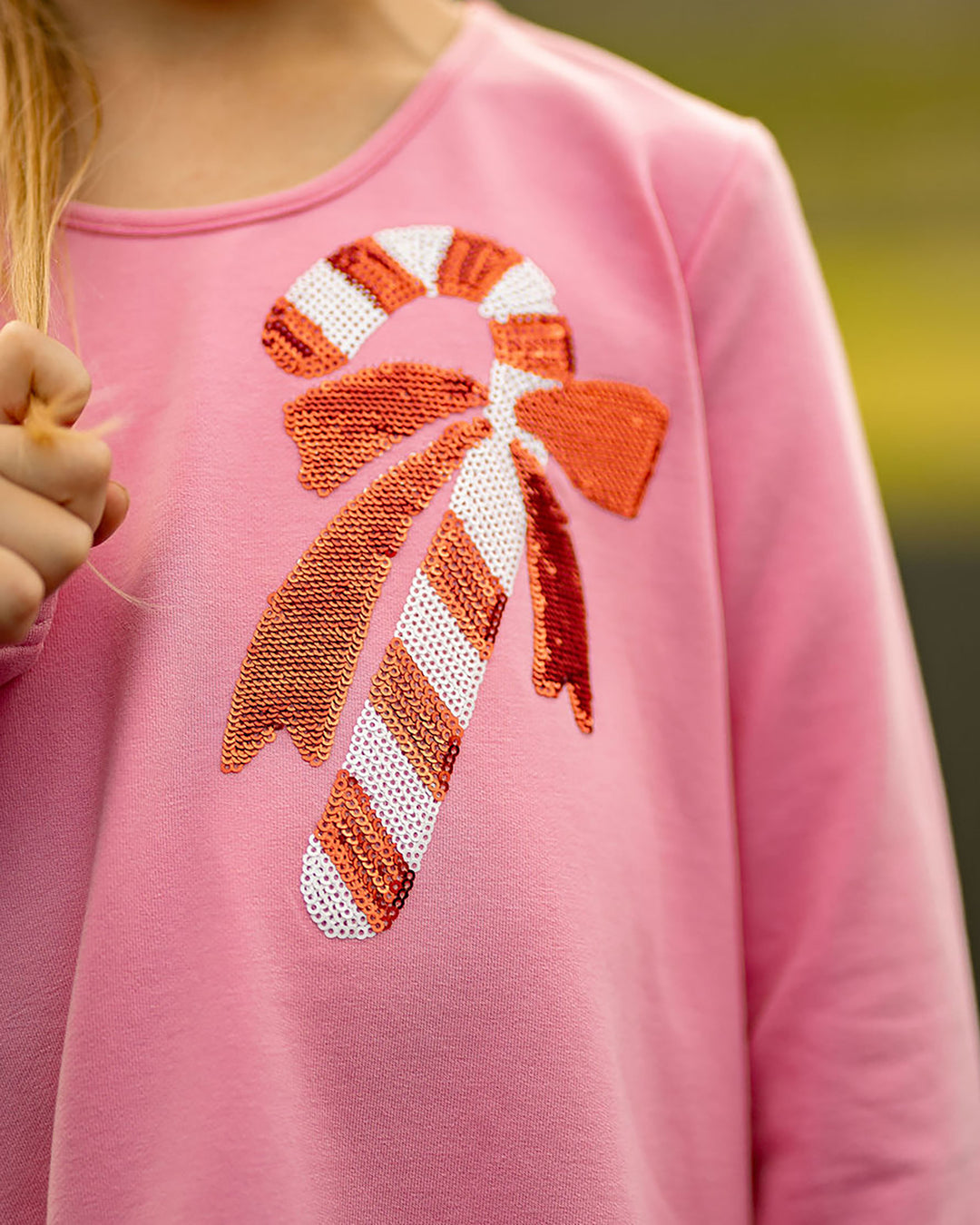 Pink sweater with a candy cane design on a blurred background