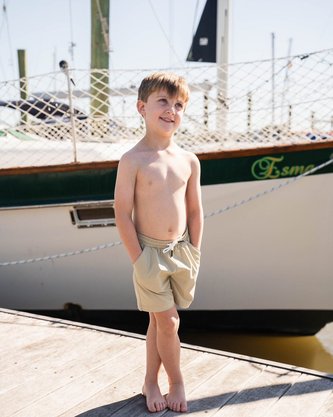 Young boy standing on a dock with a boat in the background