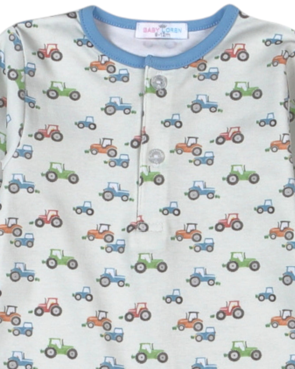 A close-up of a baby long-sleeve top featuring an all-over tractor print on a light cream background, with a contrasting light blue ribbed crew neck and a three-button henley front, that store