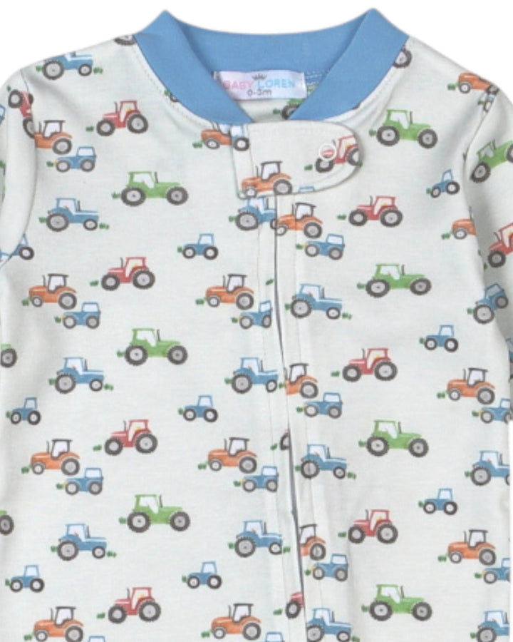 A baby long-sleeve footless sleeper with a light cream background, covered in a colorful tractor pattern, and finished with a light blue collar, that store
