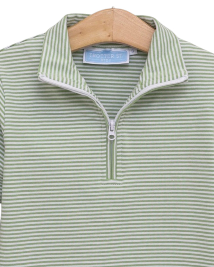 A close-up of a green and white striped quarter-zip polo shirt hanging on a wooden hanger. The shirt features a stand-up collar with white piping and a silver zipper, that store