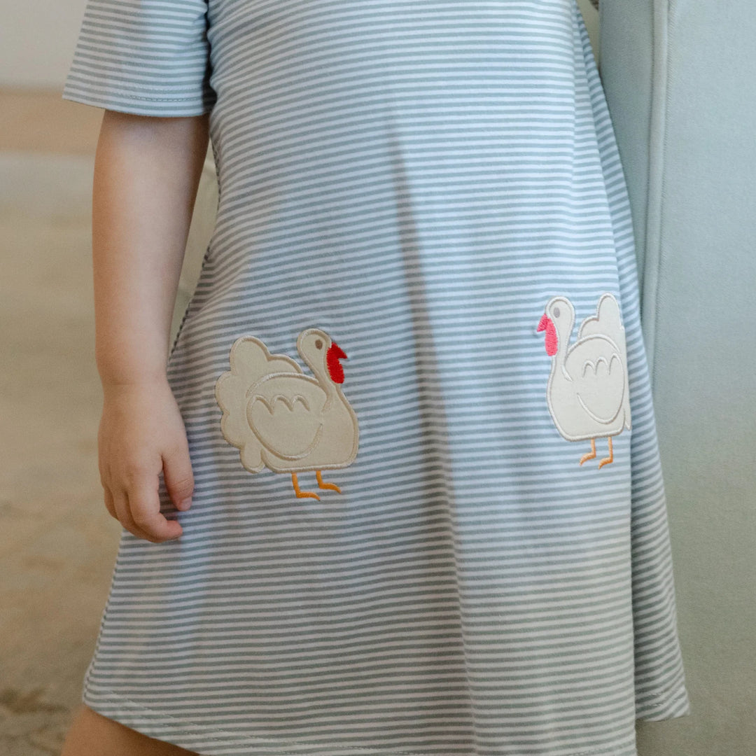 Striped dress with cartoon turkey appliqués worn by a child, that store