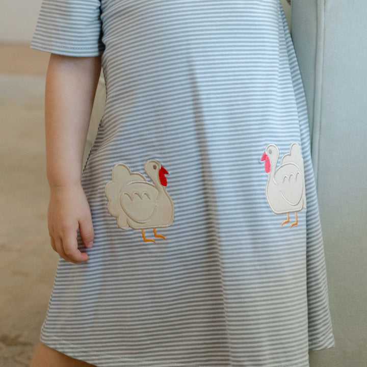 Striped dress with cartoon turkey appliqués worn by a child, that store