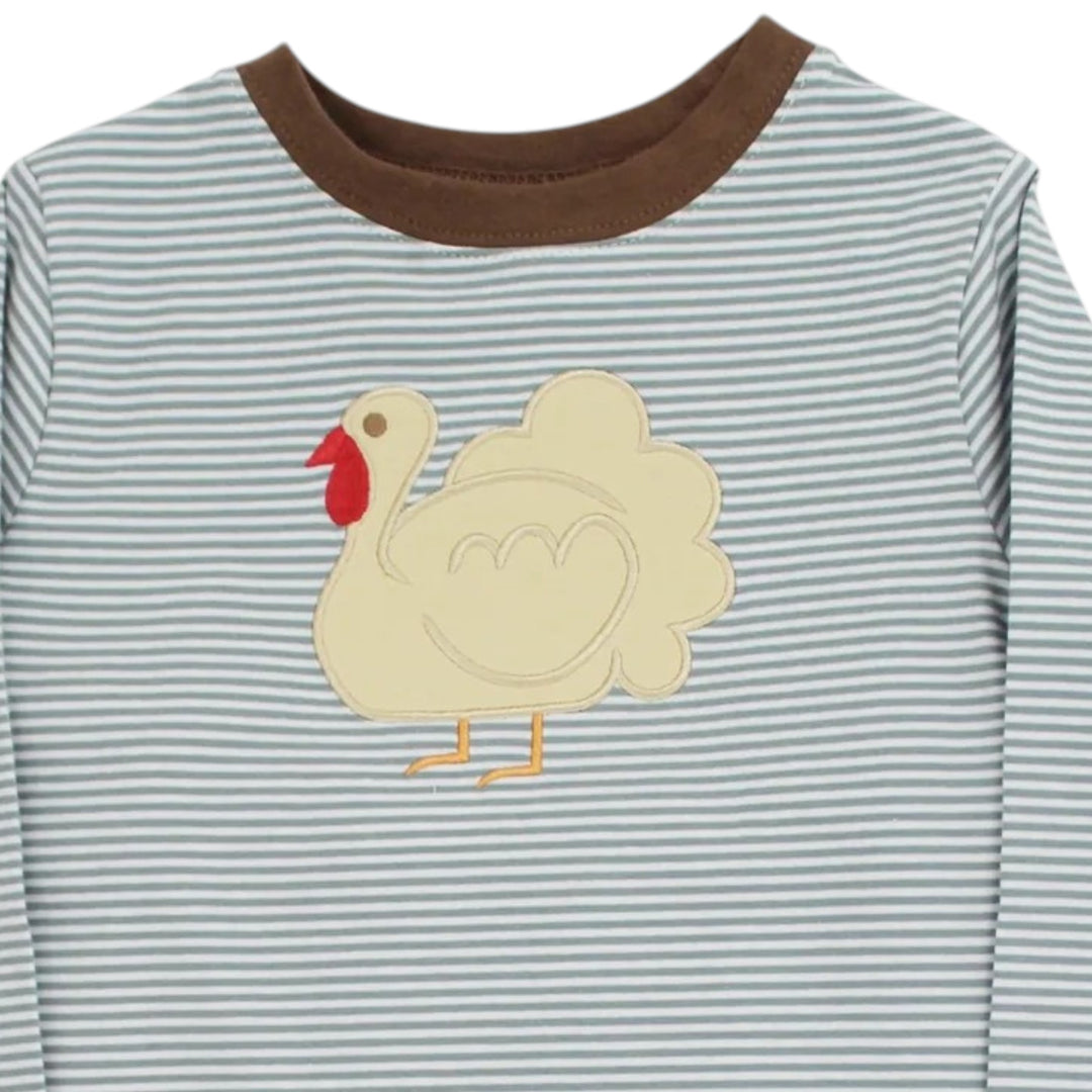 A close-up of a long-sleeve baby shirt with thin blue and white horizontal stripes, a brown ribbed crew neck, and a cream-colored applique turkey on the chest, that store