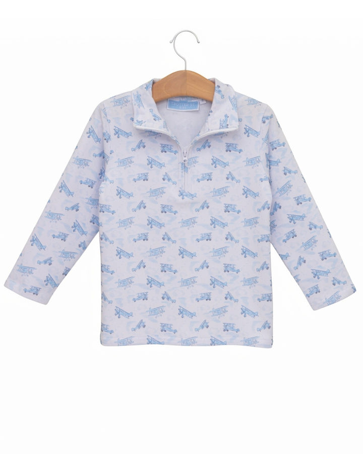 A long-sleeve baby pullover top with a light blue and white train pattern, hanging on a wooden hanger against a plain white background, that store