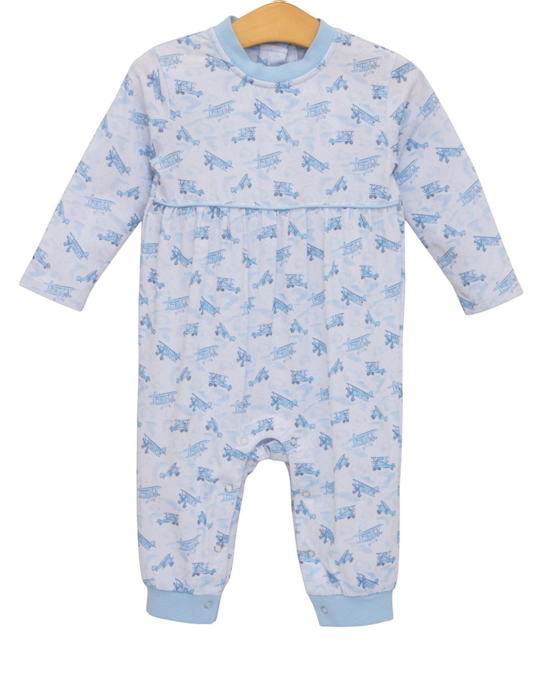 A baby long-sleeve footless one-piece jumpsuit in white with a light blue repeating airplane pattern, featuring light blue ribbed collar, cuffs, and hem, hanging on a wooden hanger against a white background, that store