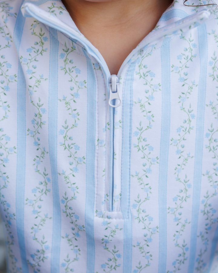 Close-up of a light blue and white striped quarter-zip top with a delicate light blue floral pattern, worn by a model, that store