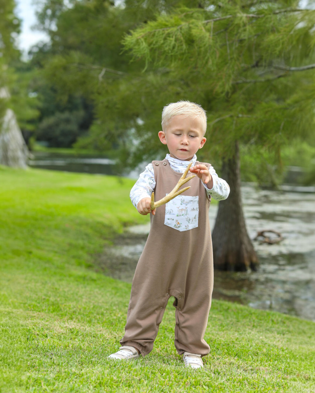 Child in a brown outfit holding a toy in a park setting
