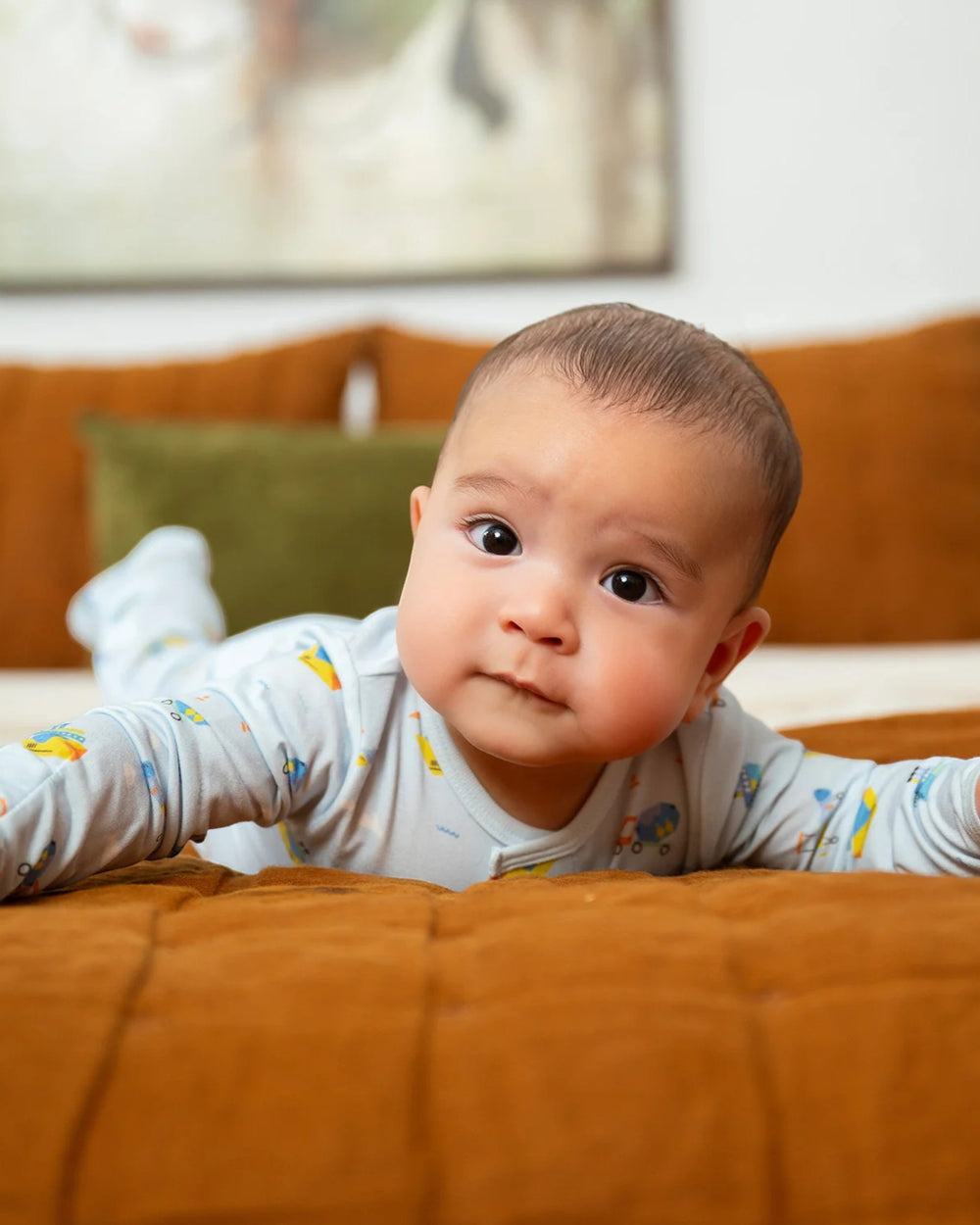 Baby lying on a brown couch with a neutral background