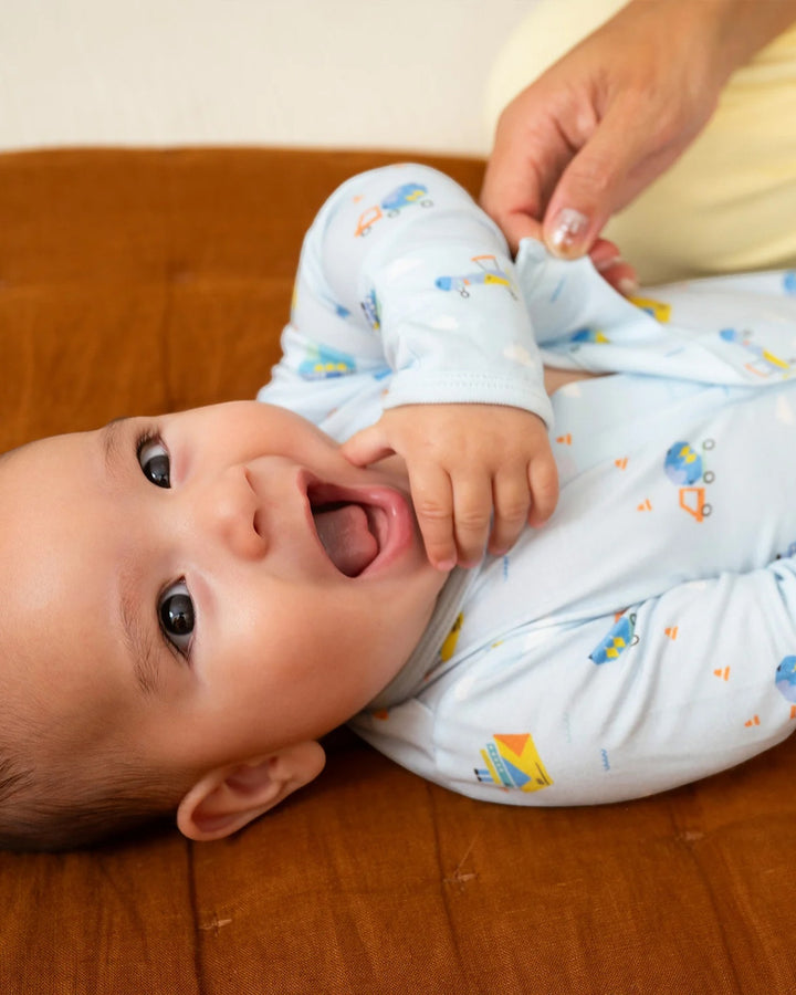 Baby lying on a wooden surface with a person adjusting their clothing