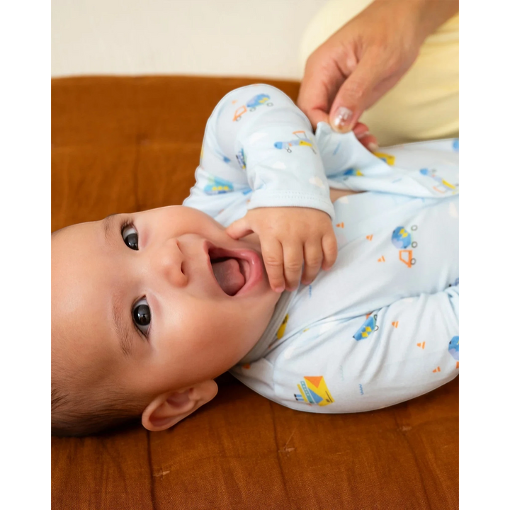 Baby lying on a wooden surface with a person adjusting their clothing