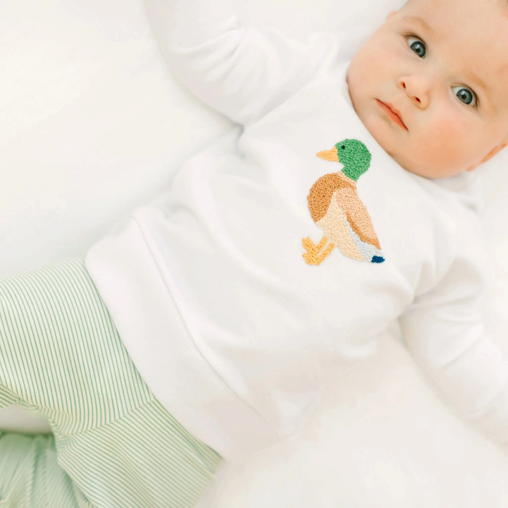 Baby wearing a white That Store Pima cotton sweatshirt with a detailed mallard duck embroidery appliqué.