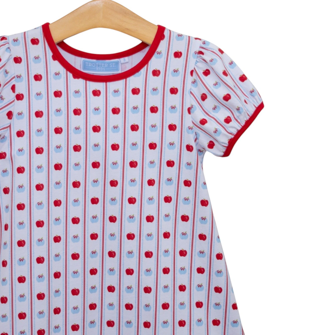 That Store girls apple print dress in white cotton with red trim and vertical stripes on a wooden hanger