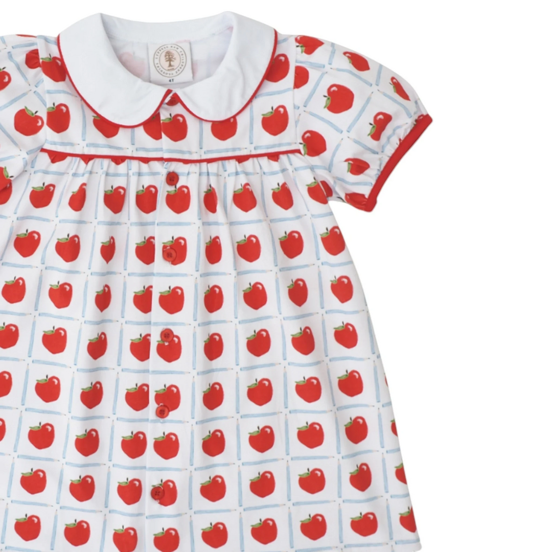 That Store Teachers Pet dress featuring a white fabric with red apple print, peter pan collar, and red button front.