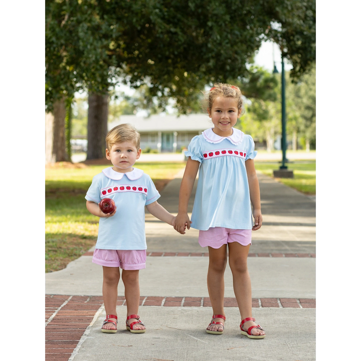 That Store boys short set in light blue with red apple ribbon trim, paired with pink gingham shorts on a young boy.