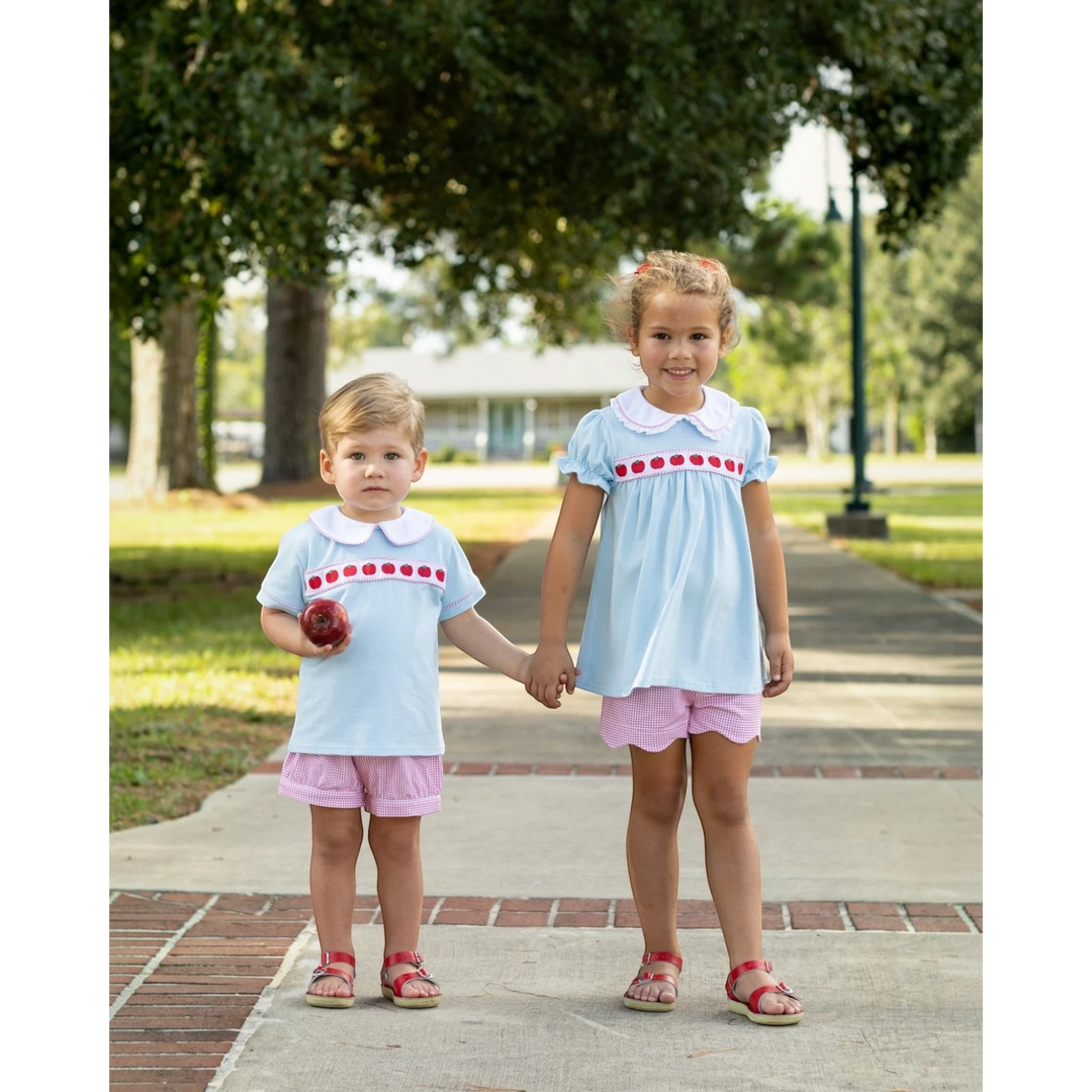 That Store boys short set in light blue with apple ribbon trim, paired with pink gingham shorts on a young boy.
