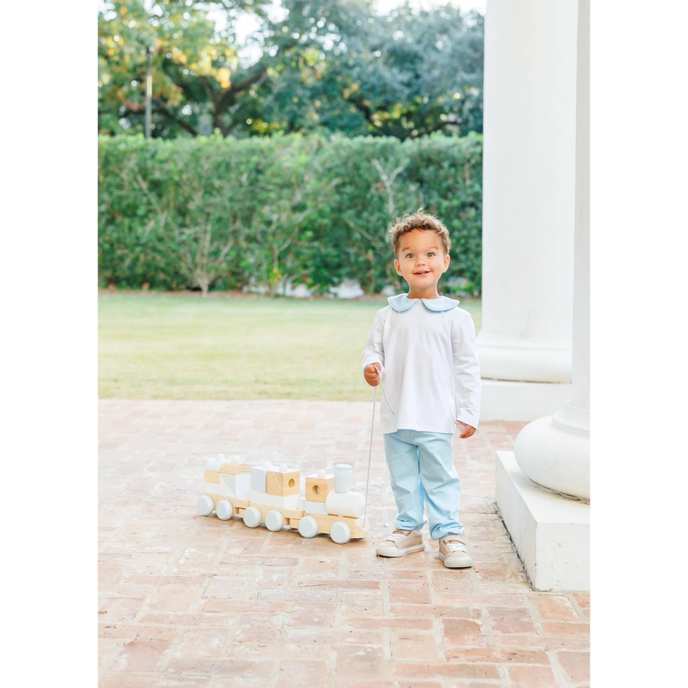 Toddler boy wearing a That Store light blue Archie bloomer pant set with a Peter Pan collar, playing with a toy train.