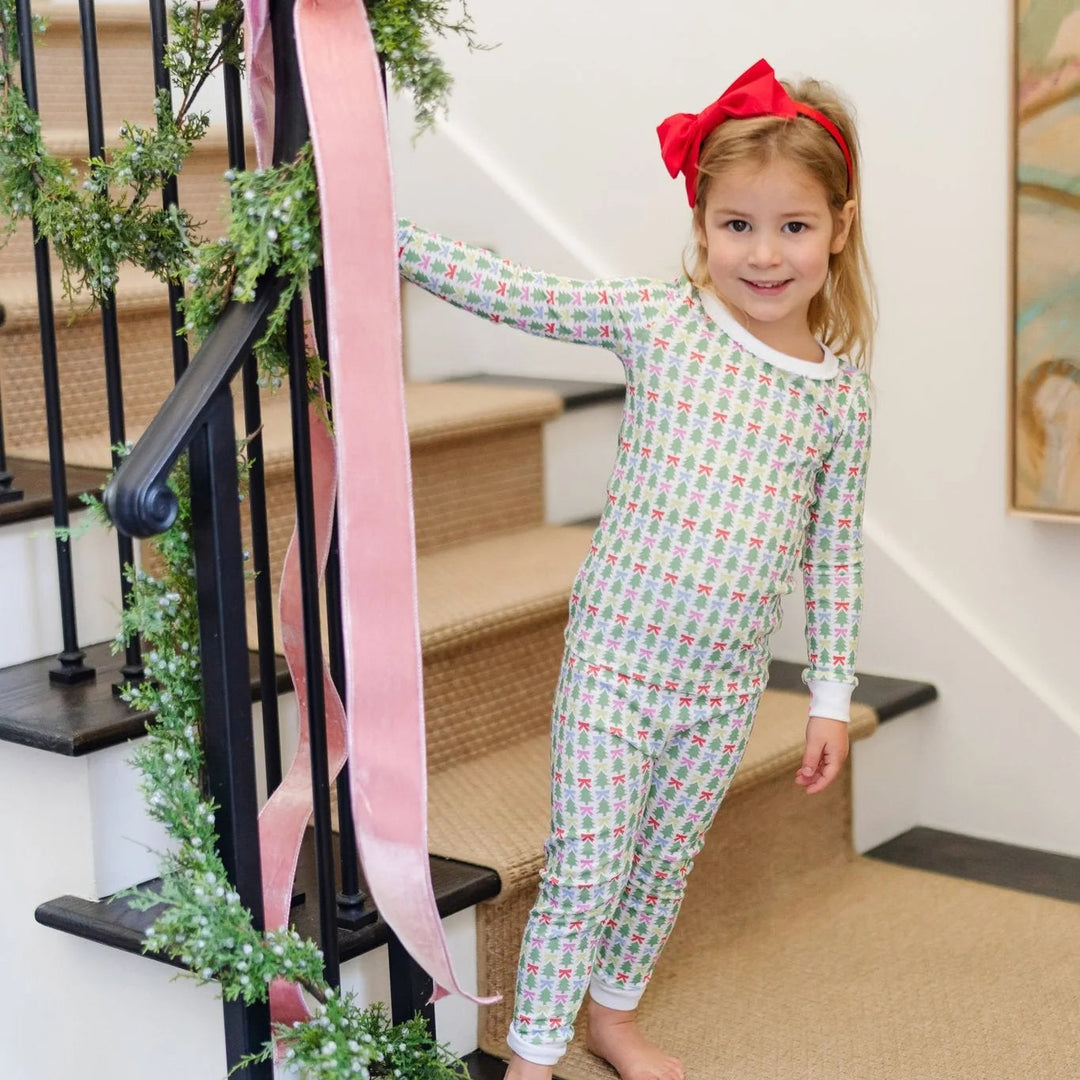 That Store Ava girls' pajama set in green Christmas tree and bow print with ruffled neckline on a smiling young girl