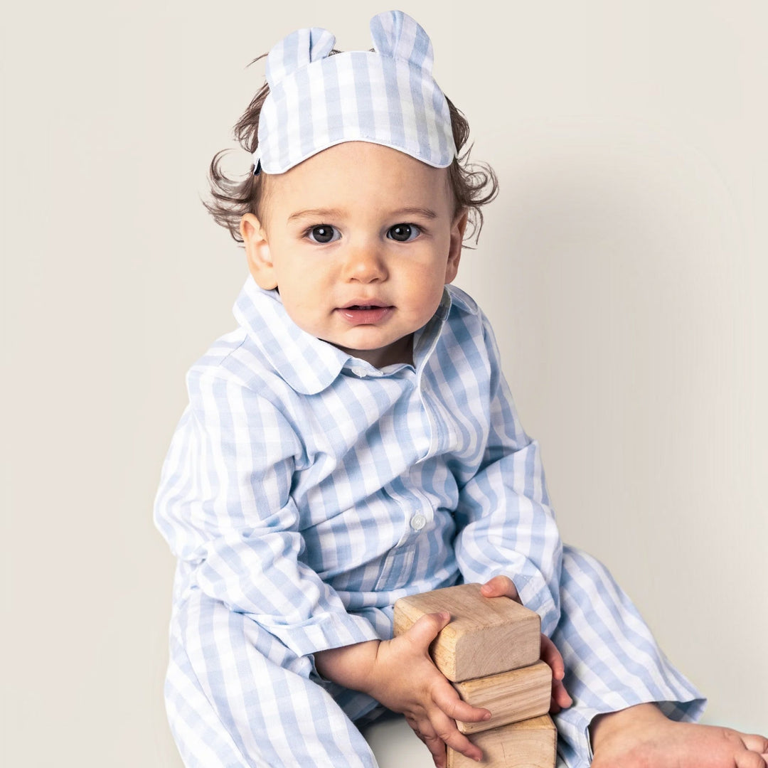 That Store baby wearing a light blue gingham cotton romper and matching sleep mask while playing with wooden blocks