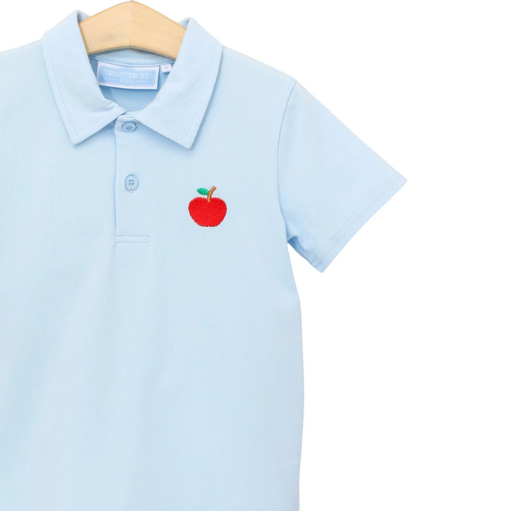 That Store light blue boys polo shirt with a red apple embroidery on the chest, made from soft cotton blend fabric.