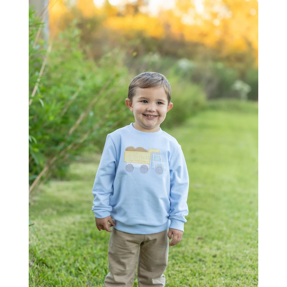 That Store blue French terry boys pullover featuring a cute dump truck graphic, worn by a smiling toddler outdoors.