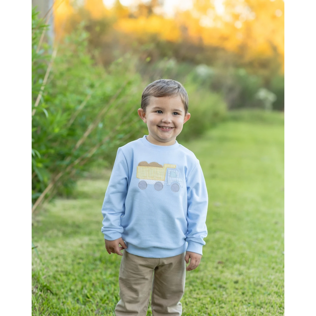 That Store blue French terry boys pullover featuring a cute dump truck graphic, worn by a smiling toddler outdoors.