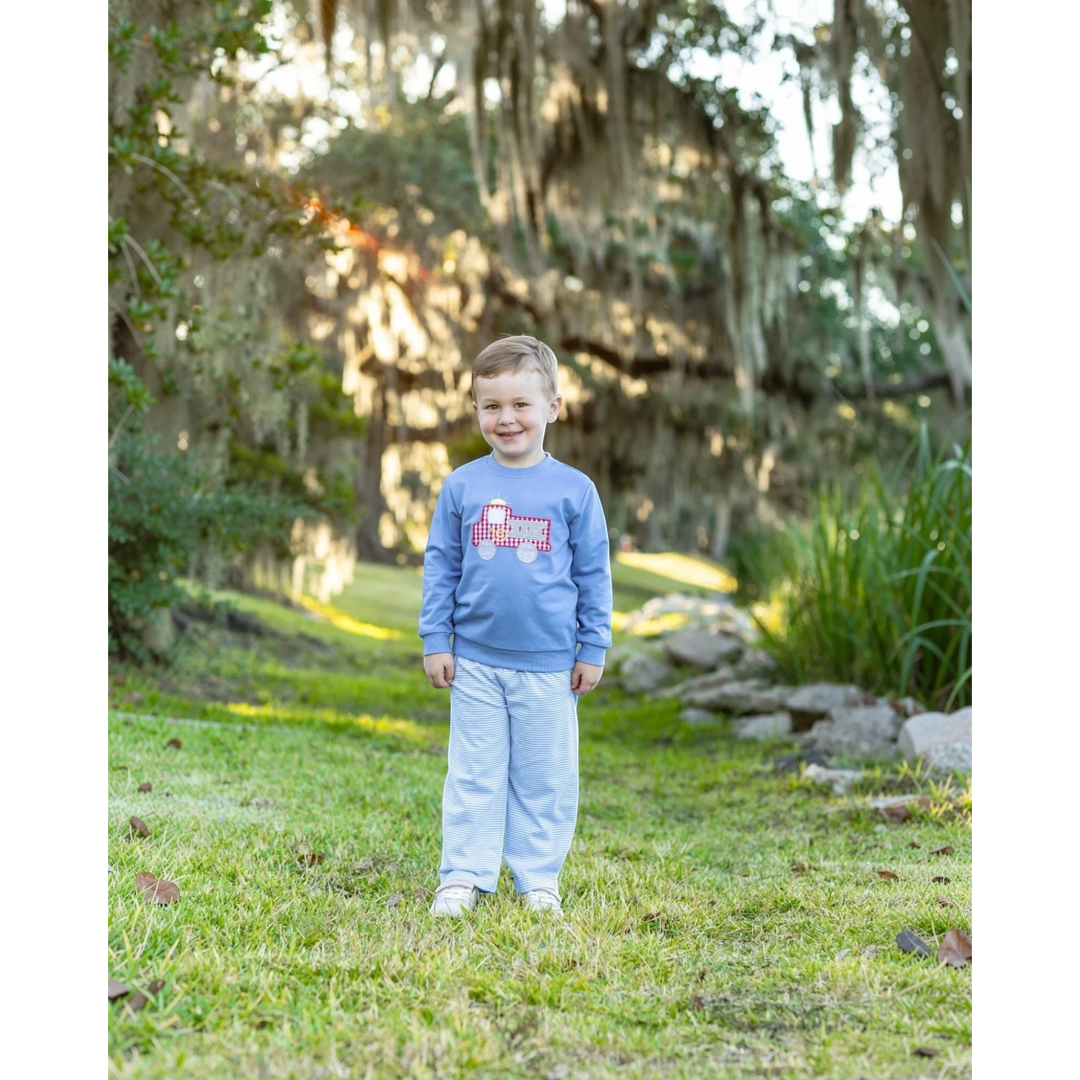That Store blue French terry pullover with a red fire truck design worn by a young boy in a park setting.