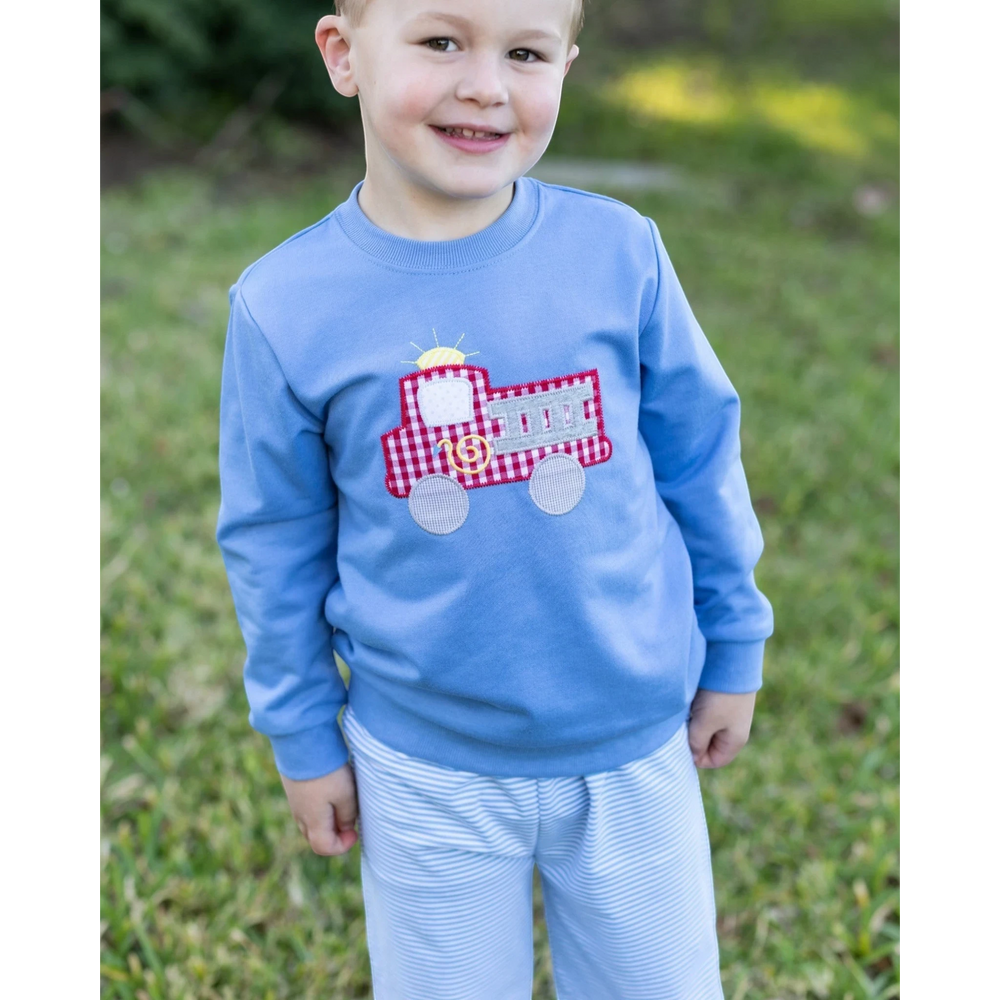 That Store blue French terry pullover for boys featuring a red gingham fire truck applique, worn outdoors.