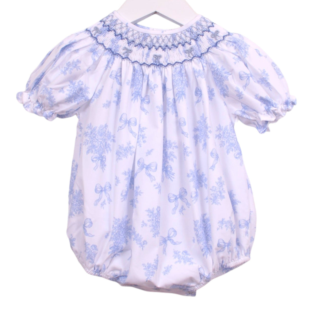 That Store girls bubble in white with blue floral print, smocked neckline, and blue bow accents.