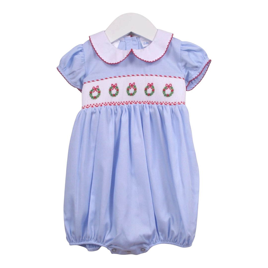 That Store blue girls bubble with smocked Christmas wreath embroidery, white peter pan collar, and red trim.