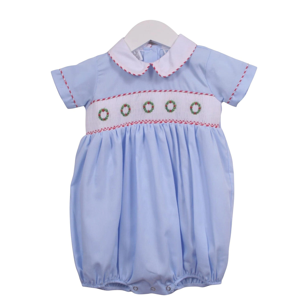 That Store blue boys bubble with smocked Christmas wreath embroidery, white collar, and snap closure.