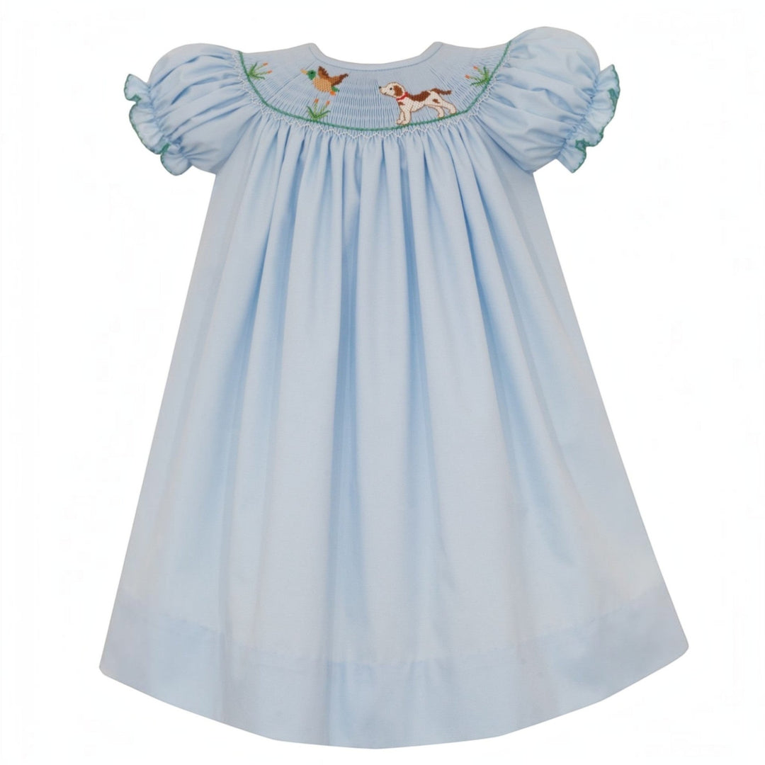 That Store blue smocked bishop dress for girls featuring hand-embroidered hunting dog and mallard duck details.