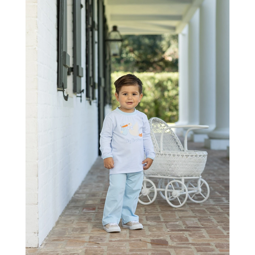 Toddler boy wearing a That Store blue striped long-sleeve shirt with a stork applique and light blue pants outdoors.