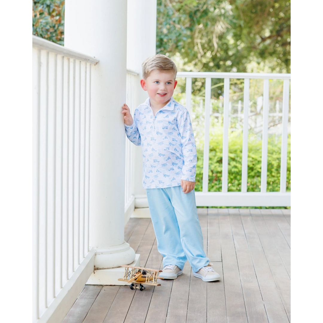 That Store boys blue airplane print 1/4 zip cotton pullover worn by a young boy on a porch with a toy plane