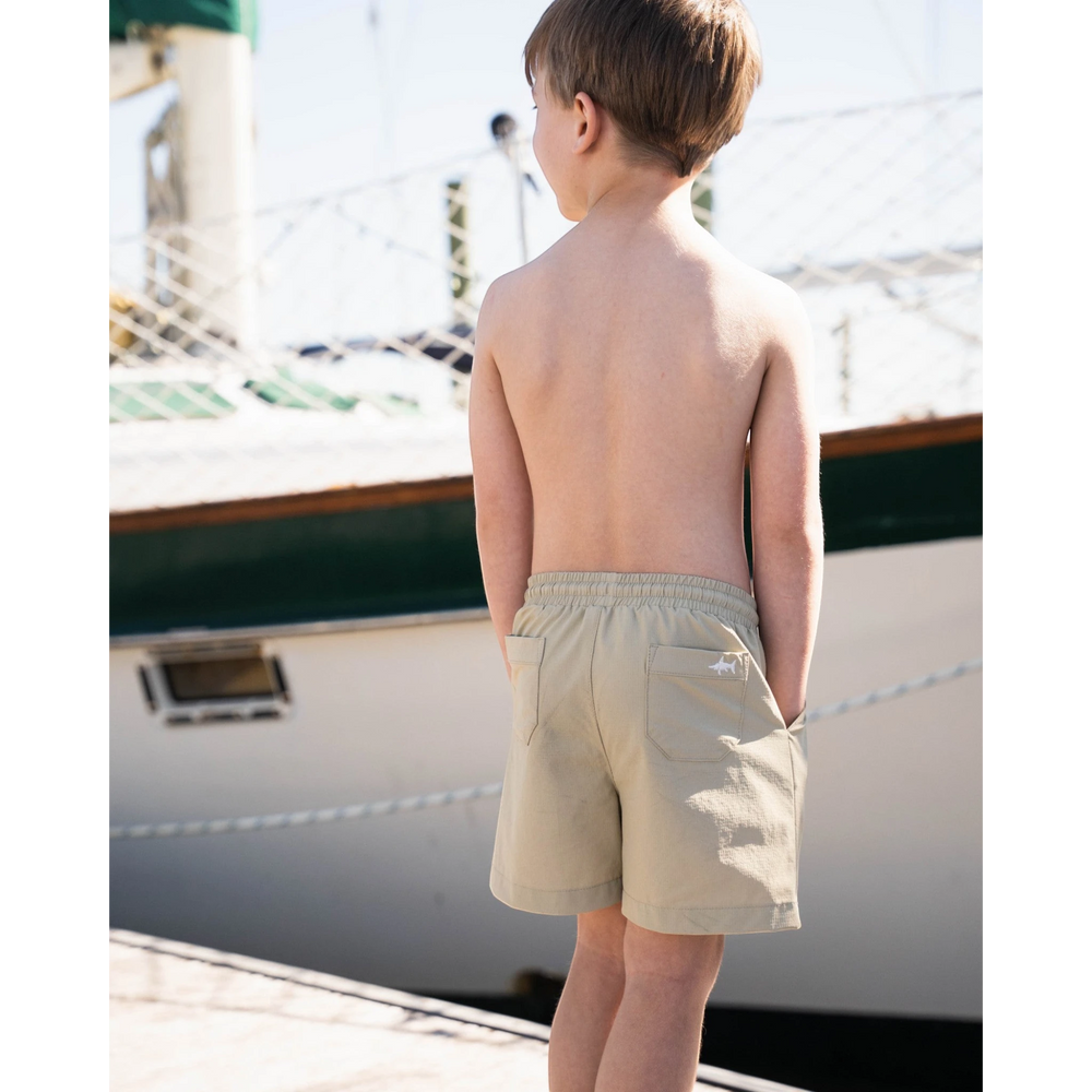 Boy wearing That Store khaki performance shorts with elastic drawstring waist and back pocket on a boat dock