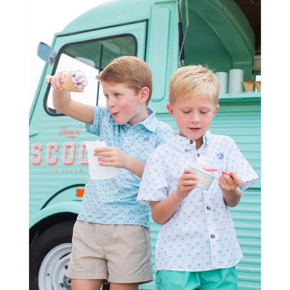 Two boys wearing That Store performance shirts and khaki shorts eating ice cream in front of a mint green food truck
