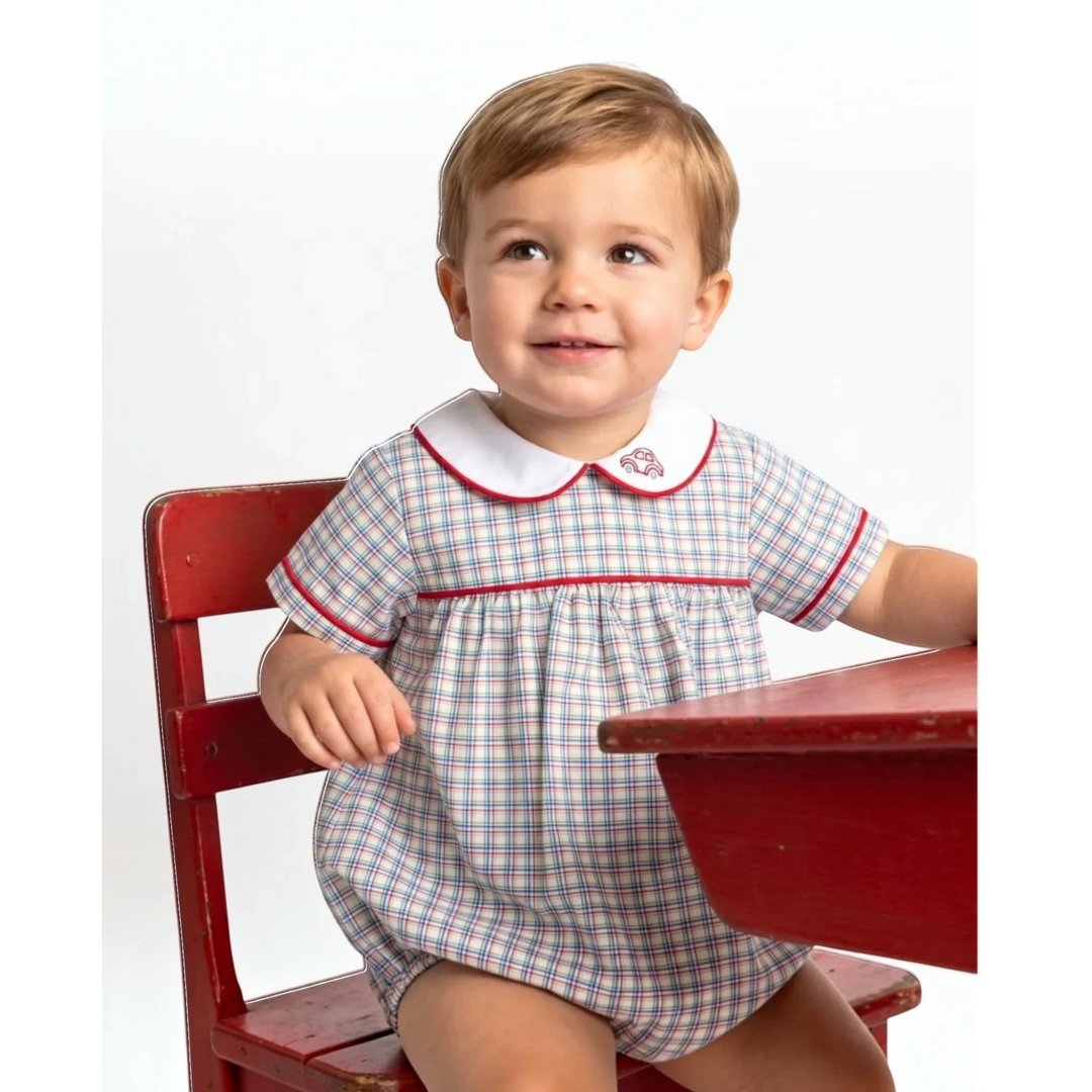 That Store boys bubble in primary plaid with red trim and car embroidery, worn by a toddler sitting at a red desk.