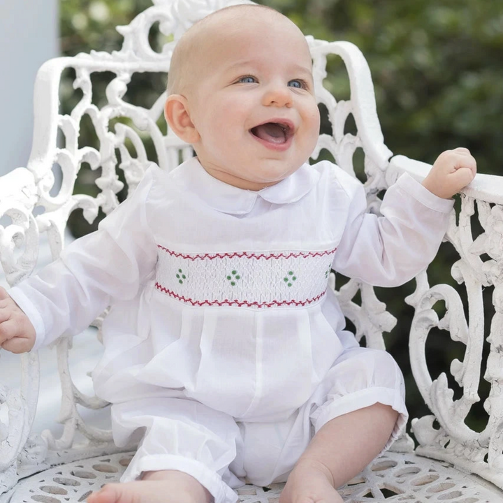 That Store baby boy white longall with red and green hand-smocked embroidery and a delicate lace-edged collar.