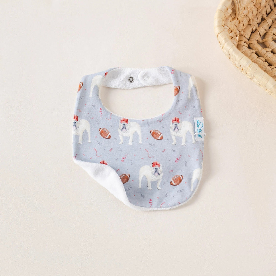 That Store organic cotton baby bib featuring a bulldog and football print with a soft white terrycloth back