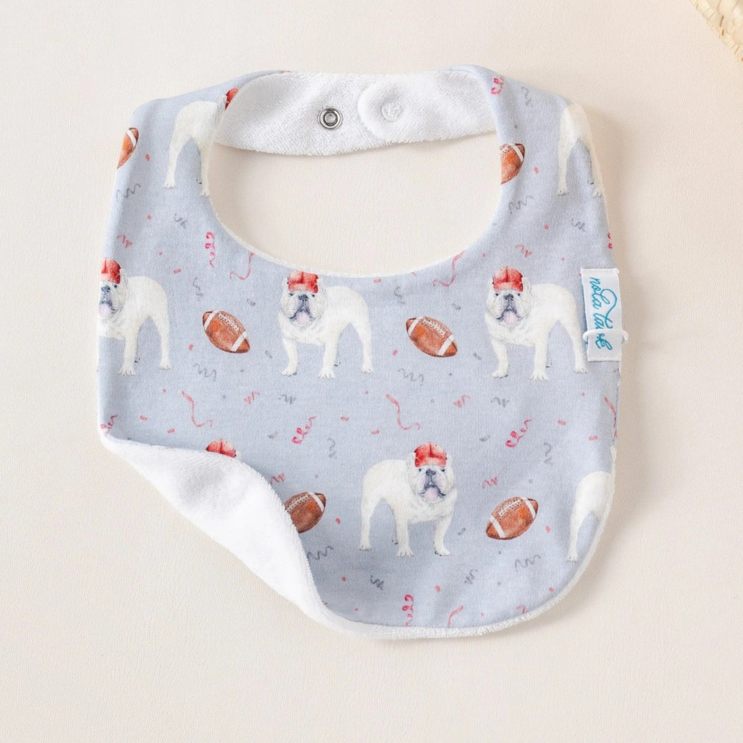 That Store organic cotton baby bib featuring a bulldog and football print with an absorbent white terrycloth back.