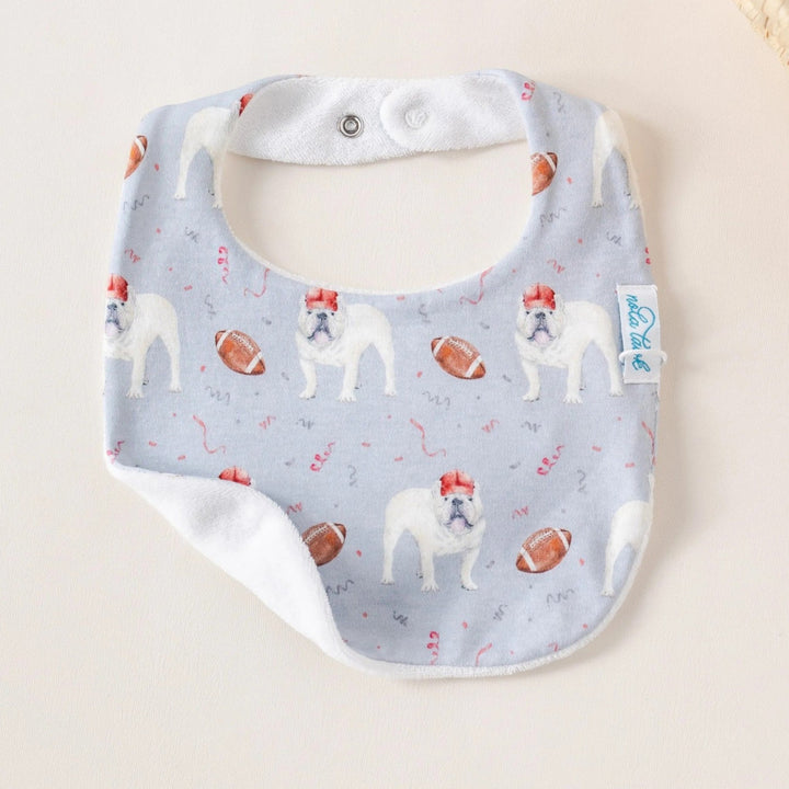 That Store organic cotton baby bib featuring a bulldog and football print with an absorbent white terrycloth back.