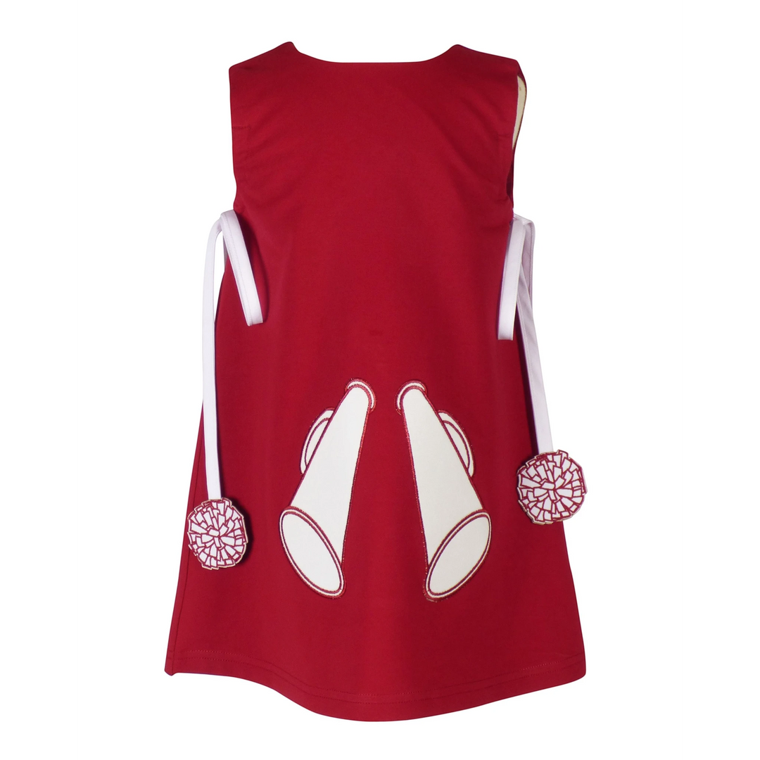 That Store burgundy cotton jumper dress for girls with white megaphone appliques and pom-pom trimmed side ties.