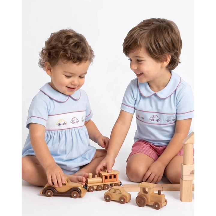 Two children wearing That Store Carson short sets in Bluffton Blue with car embroidery playing with wooden toy cars.