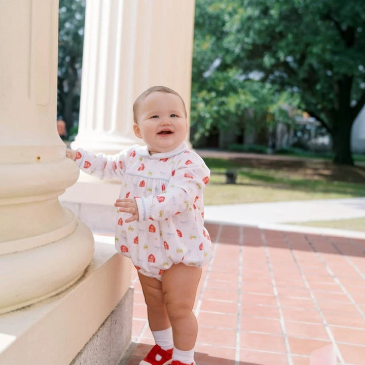 That Store Covington bubble in white knit with Barnyard Tales print, long sleeves, and light blue piping on a baby.