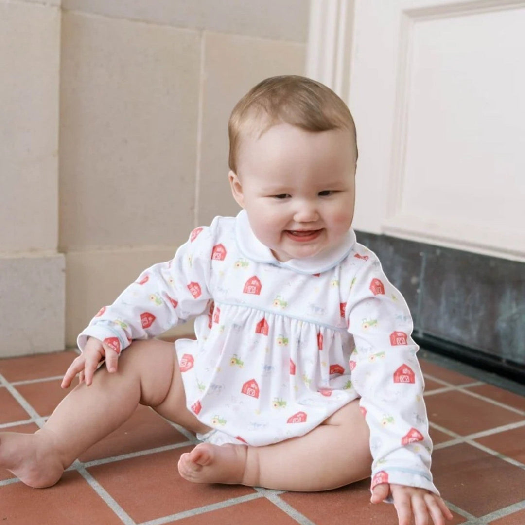 That Store Covington bubble in white knit with barnyard tales print and light blue piping worn by a baby