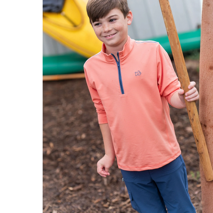 That Store Sporty Snap Pullover in crabapple orange with a stand-up collar worn by a smiling boy outdoors
