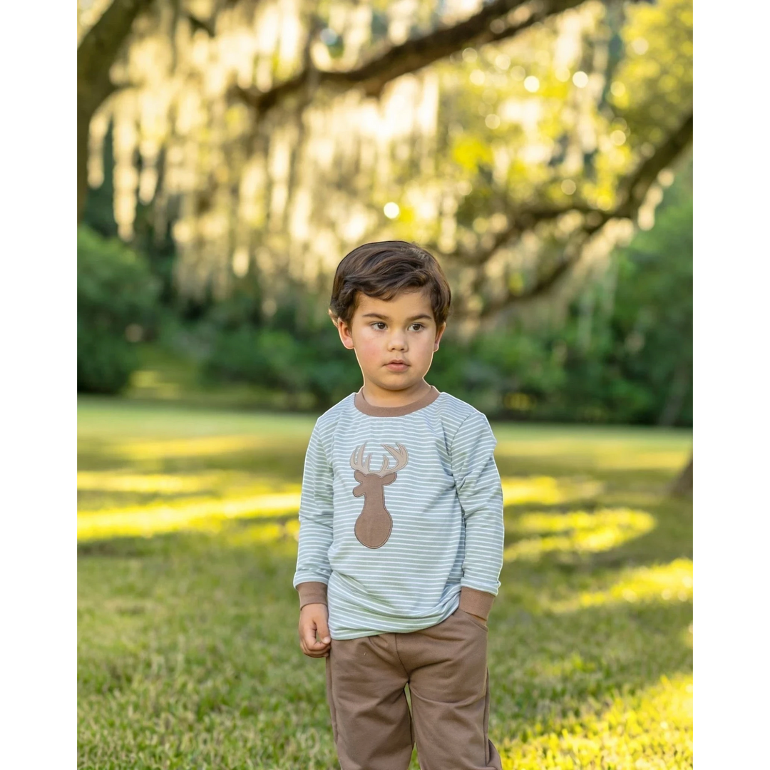 That Store boy wearing a green striped long-sleeve shirt with a deer applique and brown jogger pants in a park.
