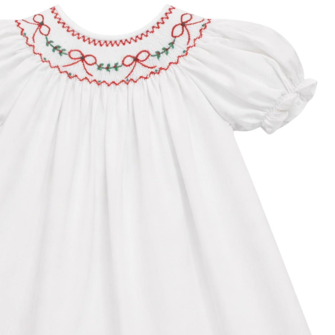 That Store white cotton girls dress featuring red bow and green holly embroidery on a scalloped collar